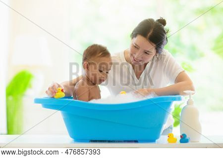 Baby Boy In Bath. Mother Washing Infant Child. Cute Little Toddler Playing With Soap Foam In White S