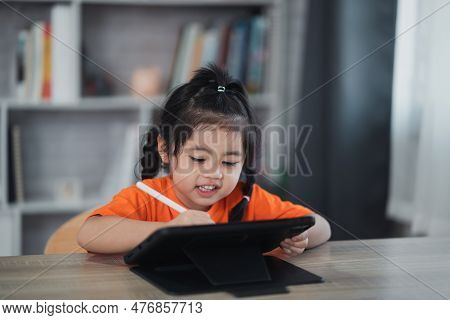Asian Girl Use Digital Pen And Touch On Screen Tablet Screen Attentively. Overstimulated Children Co