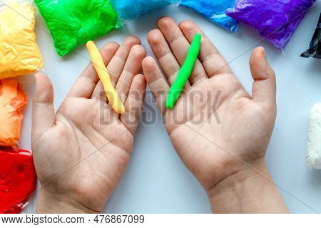 The Child Holds In His Hands Green And Yellow Plasticine, Rolled Into A Flagellum.