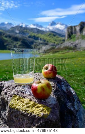 Glass Of Natural Asturian Cider Made From fermented Apples With View On Covadonga Lake And Tops Of P