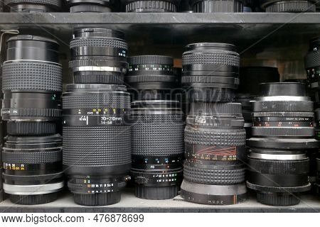 Stack Of Camera Lenses And Doubleurs On A Shelf.