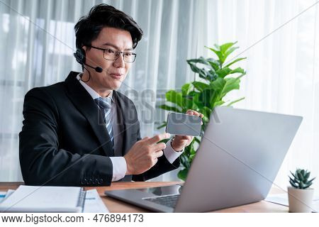 Confident Asian Telesales Businessman Work In Modern Office Wearing Headphone, Presenting Bi Dashboa