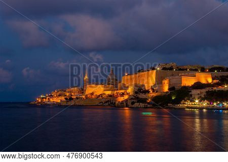 The Cityscape Glows In The Evening Light, Illuminated By A Sky Of Pastel Hues And Reflected In The S