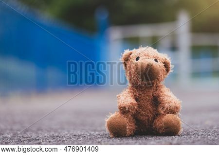Lost Teddy Bear Toy Sitting  On Playground Floor In Gloomy Day,lonely And Sad Brown Bear Doll Sittin