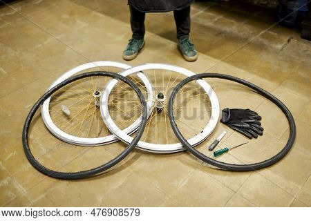 Bicycle Wheels And Airless Tires Disassembled On The Floor Of A Bike Repair Shop. White Rims, Orange