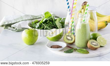 A Green Smoothie Surrounded By Fresh Raw Ingredients Used To Make It.