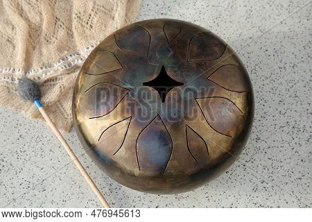 Steel Tongue Drum And Soft Mallet On Grey Table, Above View. Percussion Musical Instrument