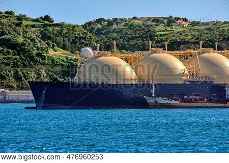 Lng Or Liquified Natural Gas Tanker Moored By Industrial Pier And Green Hill On Sunny Day. Alternati