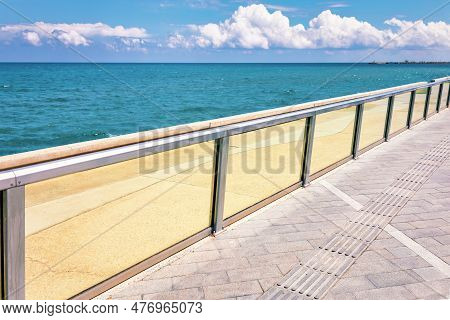 Seaside With Glass Balustrade . Sidewalk On The Sea Shore