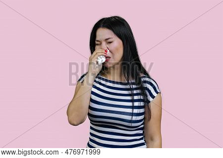 Sick Asian Young Brunette Woman Is Sneesing In A Hankerchief. Isolated On Pink Background.