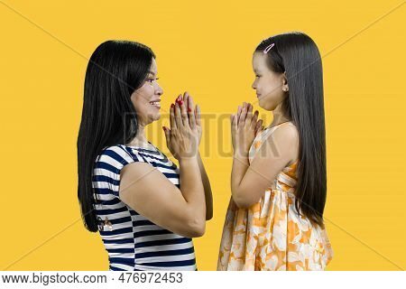 Side View Of A Young Mother And Her Daughter Are Playing Clapping Game Cutout. Isolated On Yellow.