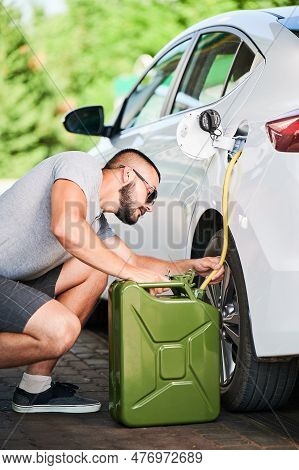 Man Stealing Gasoline From Car Tunk. Thief Trying To Pump Fuel From Someone Elses Automobile. Steali