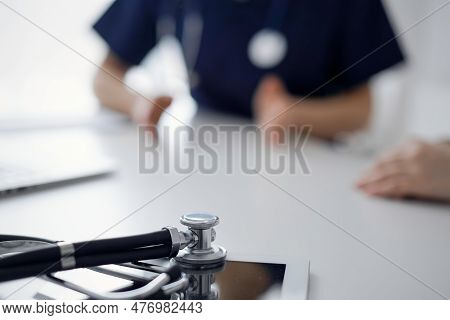 Stethoscope Lying On The Tablet Computer In Front Of A Doctor And Patient At The Background. Medicin