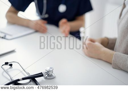 Stethoscope Lying On The Tablet Computer In Front Of A Doctor And Patient At The Background. Medicin
