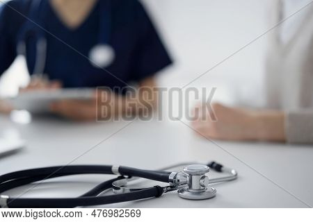 Stethoscope Lying On The Tablet Computer In Front Of A Doctor And Patient At The Background. Medicin