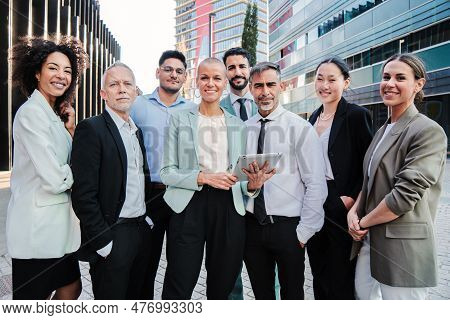 Team Work Of Businesspeople Standing At Workspace And Looking At Camera Together. Meeting Of A Crowd