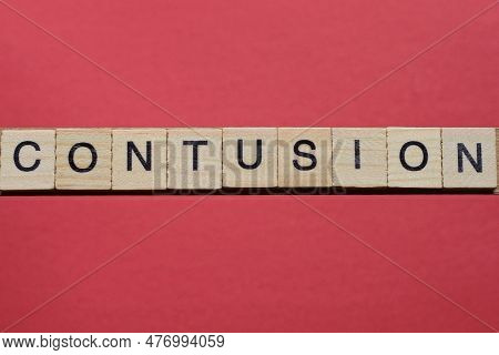 Text The Word Contusion From Gray Wooden Small Letters With Black Font On An Red Table