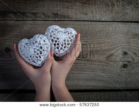 Valentines day background. White lace hearts in womans hands.