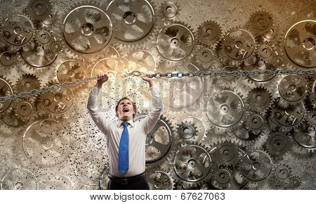 Young furious businessman breaking metal chain with hands