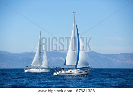 Group of sail yachts in regatta near a coast.