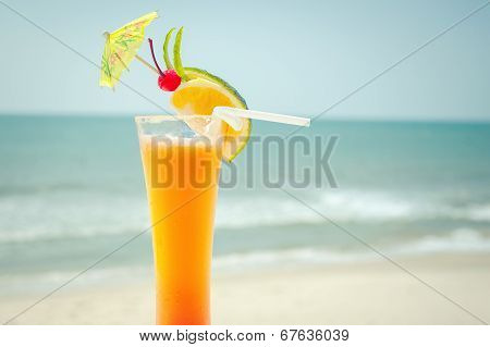 Tequila Sunrise Cocktail With Fruits And Umbrella Decoration At Tropical Ocean Beach