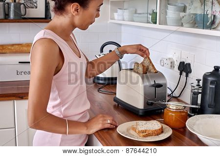 young woman making breakfast toast bread with toaster at home kitchen