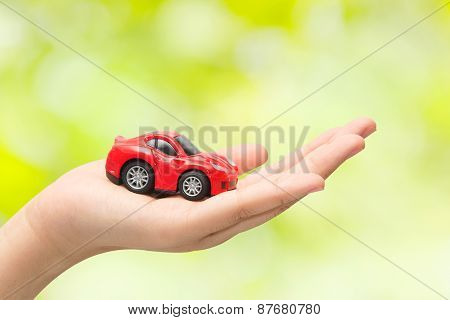 Hand Holding The Model Of Car On Green Background. Symbol Photo For Car Purchase