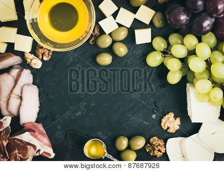 Wine Appetizer Set: Cheese And Meat Selection With Grapes, Honey, Olives And Walnuts On Black Stone