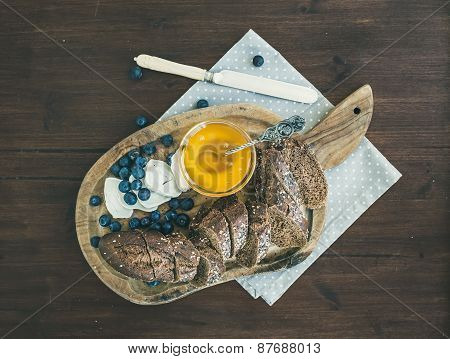 Breakfast Set On A Dark Wood Background: Fresh Dark Baguette Cut In Slices, Goat Brie Cheese, Bluebe