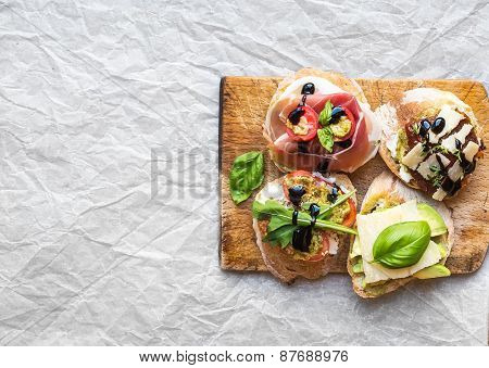 Bruschetta Set On A Rustic Wooden Board Over A White Paper Surface With A Copy Space
