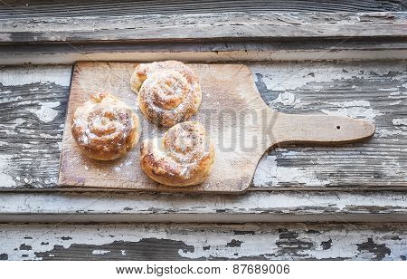 Cinnamon Buns On A Rustic Wooden Board