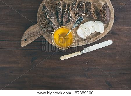 Fresh Dark Baguette Cut In Slices, Goat Brie Cheese And Honey On A Rustic Wooden Board