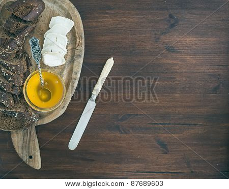 Fresh Dark Baguette Cut In Slices, Goat Brie Cheese And Honey On A Rustic Wooden Board