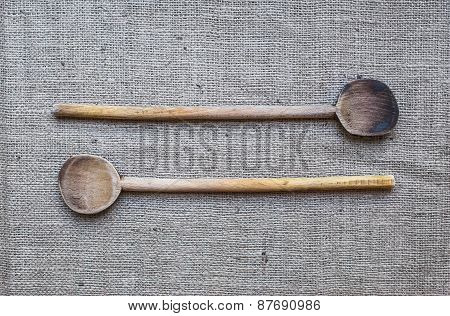 Two Rustic Wood Cooking Spoons Over A Sackcloth Surface