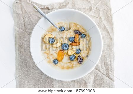Oat Porridge With Fresh Blueberry, Nuts And Honey In A White Ceramic Bowl On White