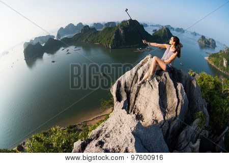 A young traveler girl sit on the top of mountain and enjoy the beauty of seascape