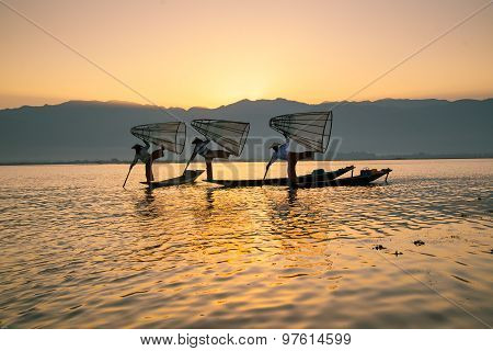 Three fishermen catches fish for food in sunrise in Inle Lake, Myanmar