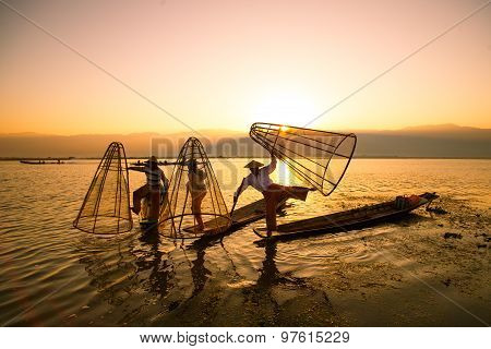 Three fishermen catches fish for food in sunrise in Inle Lake, Myanmar