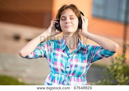 Young beautiful girl listening to music player on the street.