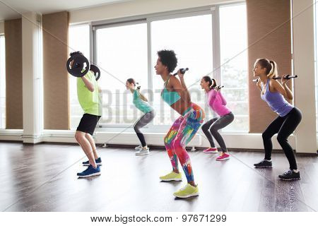 fitness, sport, training, gym and lifestyle concept - group of people exercising with barbell and bars in gym
