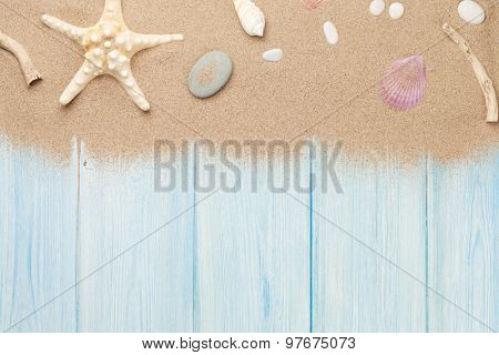 Sea sand with starfish and shells on wooden table. Top view with copy space