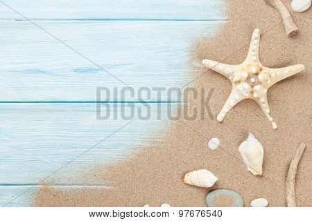 Sea sand with starfish and shells on wooden table. Top view with copy space