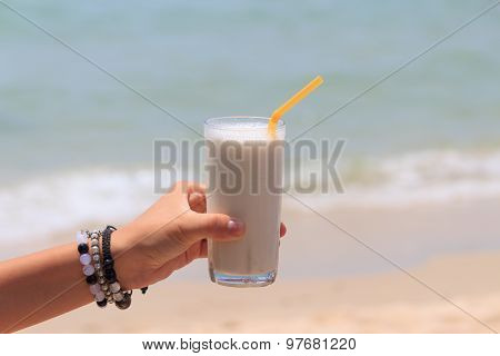 Female Hand Holding Milk Shake With Tropical Sea View Background