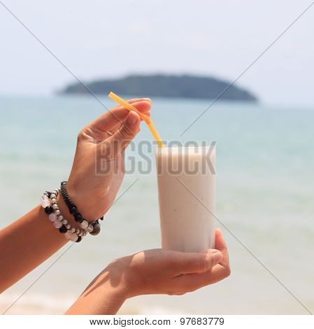Female Hand Holding Milk Shake With Tropical Sea View Background