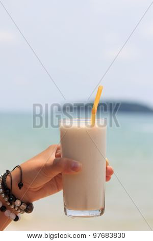 Female Hand Holding Milk Shake With Tropical Sea View Background