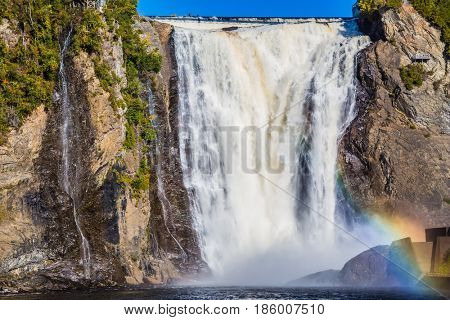 Magnificent rainbow in the spray of the waterfall Montmorency in Montmorency Falls Park. The concept of active and cultural tourism