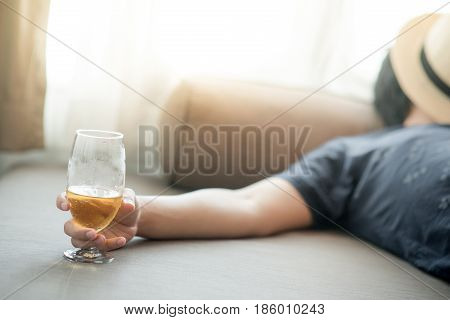 drunken man sleeping while holding a glass of beer in bedroom hangover after holiday party alcoholism or alcohol addiction concepts