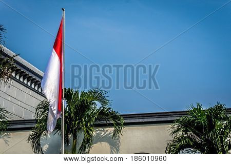 Indonesia flag on the mast with building as background photo taken in indonesia java
