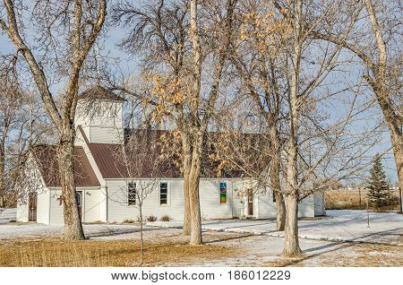 White country church with a new brown steel roof on a winter day