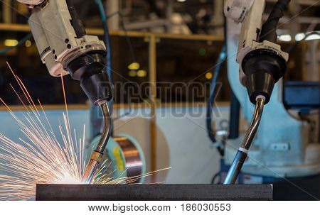 Close up in team industrial robots are welding in factory